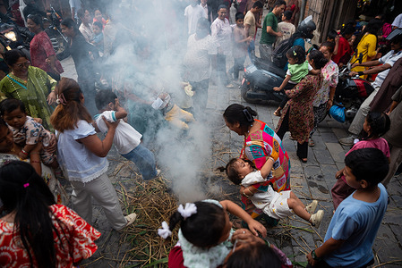 A devotee lifts his child over the fire as part of the celebration during the festival. Ghantakarna festival is a celebration of the defeat of the mythical demon Ghantakarna, chasing the evil spirits and bringing good fortunes.