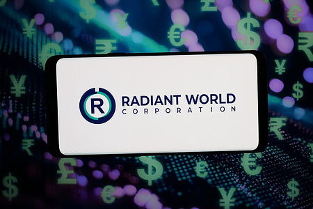 In this photo illustration, the logo of commodity trading company Radiant World is displayed on a smartphone in front of abstract background on computer screen.