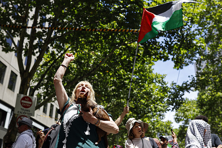 A protester raises her fist during the rally. Hundreds of protesters rallied in Melbourne in support of Palestine and Palestinians. Marching from the State Library to Parliament of Victoria, the demonstration highlighted calls to end the genocide, apartheid, and occupation in Gaza.