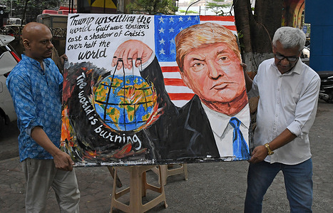 Teachers from Gurukul school of art carry back a poster painted with a message 'Trump unsettling the world. Gulf war tension cast a shadow of crisis over half the world' outside the art school in Mumbai.