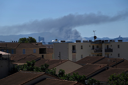 View of a plume of smoke from a fire rising above buildings in Marseille's northern districts, while a boat burns at the Old Port. A fire broke out on board a vessel in Marseille's Old Port, near the town hall, before spreading to another twenty-meter-long boat.