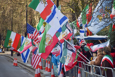 Protesters hold Iranian, Israeli and USA flags during the demonstration. Crowds gathered outside the Embassy of Iran in protest against the Islamic Republic and in support of Reza Pahlavi, the Crown Prince of Iran.
