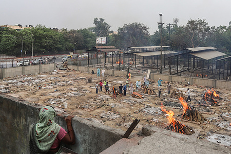 A woman looks at relatives of coronavirus (Covid-19) victims performing the last rites during a cremation at a crematorium in New Delhi.
India reports 3,66,161 new cases, 3,754 deaths in the last 24 hours.