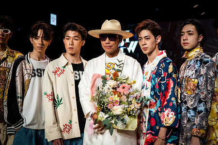 ISSUE founder Bhubawit Kritpholnara poses with flowers and some models at the end of their runway show. ISSUE, presented by TAT (Tourism Authority of Thailand), premiers its new collection as part of Bangkok International Fashion Week, Day 1, at Siam Paragon in Bangkok.