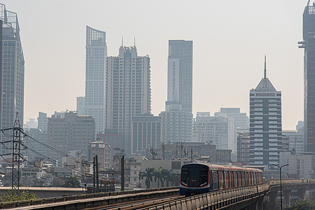View of high-rise buildings and BTS Skytrain amid smoggy conditions due to air pollution in Bangkok. Bangkok, the capital of Thailand, is experiencing poor air quality as fine particulate matter (PM 2.5) caused by different factors such as crop field burning and vehicle exhaust emissions.