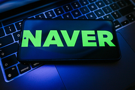 In this photo illustration, a Naver logo is seen displayed on a smartphone on the top of a laptop.