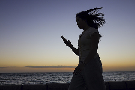 A woman is seen walking during sunset. Sunset at Point Ormond Lookout, as the city heads into the Christmas period, with residents spending time outdoors.