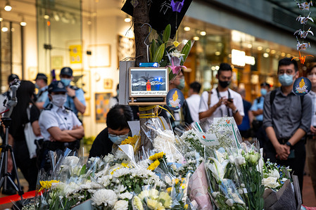 A framed piece of art hangs on a tree, as part of the makeshift shrine.
Dozens of people laid white flowers, ribbons and lit candles to commemorate the two-year death of Marco Leung Ling-kit in Admiralty, Hong Kong. He was a man who fell to his death in a yellow raincoat from scaffolding of a nearby building during a social unrest, and had become an icon for the 2019-2020 Hong Kong protests.