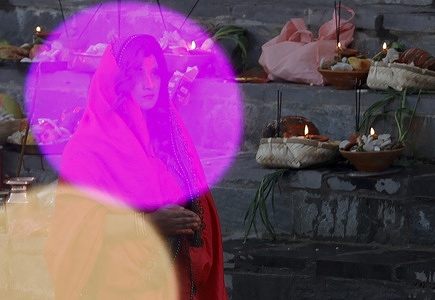 A Hindu woman holds incense sticks while offering prayers to the setting sun on the banks of the Bagmati river during the Chhath festival. On Chhath, an ancient festival observed by Hindus, devotees gather by the holy river to offer prayers by fasting, bathing, and standing in the water for continuous periods to offer prayers to the Sun God, thanking and paying respects to seek blessings for sustaining life on earth.