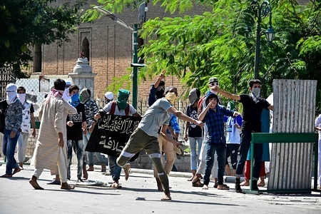 Masked protesters seen throwing stones at the Indian police during the clashes.
Clashes erupted between Kashmiri protesters and Indian government forces soon after the Friday congregational prayers ended in the Grand Mosque in Srinagar.