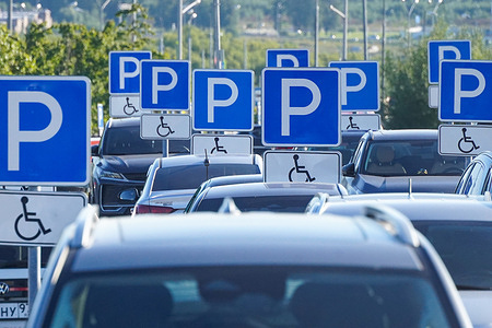A crowded parking lot filled with cars and numerous traffic signs indicating parking spaces for disabled people