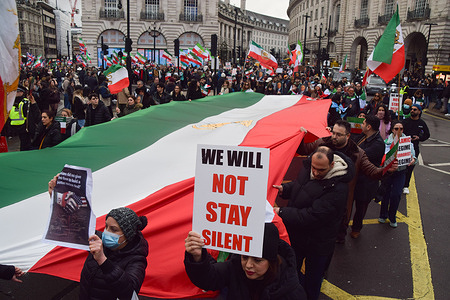 Protesters pass through Piccadilly Circus with a giant Iranian flag and a placard stating 'We will not stay silent' during a march against the Islamic Republic and in support of Reza Pahlavi, the Crown Prince of Iran.