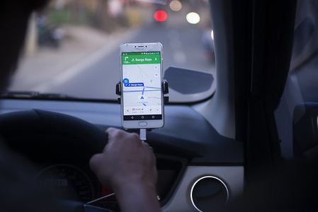An on-line taxi driver seen using gps navigate which was mounted above the car dashboard to provide driving direction at Jakarta, Indonesia.
Indonesian Constitutional Court has ruled that checking the GPS on a mobile phone while driving is punishable by up to three months' imprisonment, as stipulated in the 2009 Traffic Law.
