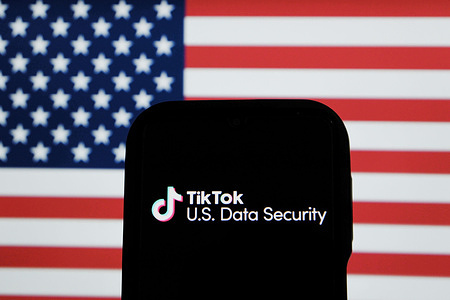 In this photo illustration, the TikTok USDS (U.S. Data Security) logo is seen displayed on a smartphone screen, and the Flag of America in the background.