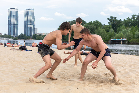 Teenagers participate in riverside beach wrestling in Kyiv city.