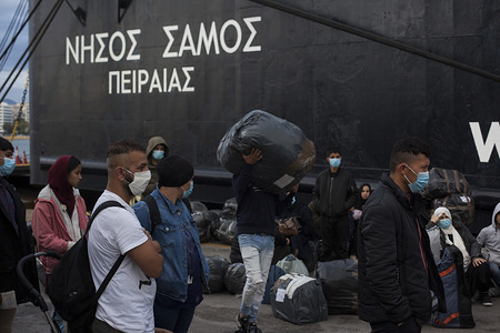 Refugees wearing face masks as a preventive measure await to board buses at the Piraeus Harbour.
249 refugees arrived at the port of Piraeus from Lesbos and Chios islands to be transferred to the mainland camps.