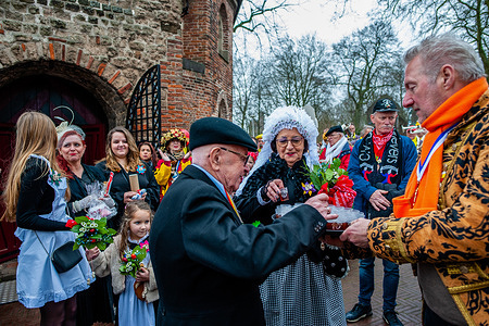 The couple seen taking drinks to toast after the ceremony. The tradition of the fake peasant wedding during carnival dates back to the sixteenth century, the nobility played the role of the peasants and the peasants were the lords. In Nijmegen, Anja and Theo Wijlemans were the farmer's wedding couple, this year. The couple gathered at the Valkhof chapel, wearing traditional farmer's clothes and surrounded by people wearing vibrant costumes. The farmer's wedding is one of the Dutch Carnival traditions, especially in Limburg, North Brabant, and Gelderland. The reversal ritual was the essence of the carnival at the time.
