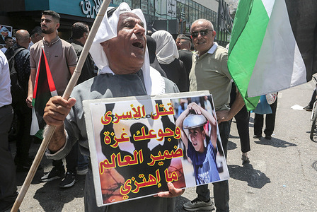 An elderly Palestinian man holds a poster during a protest march in solidarity with the people of the Gaza Strip and Palestinian prisoners.