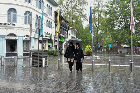 Kashmiri women with an umbrella seen walking along the street during rainfall. Rain lashed parts of Kashmir valley as the India Meteorological Department (IMD) issued a weather advisory predicting moderate to heavy rainfall over the next 36 hours as a strong Western Disturbance approaches the region