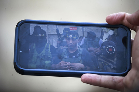 Palestinian militants from the Qabatiya Battalion are seen on a phone screen during a press conference, after an Israeli military raid in the town of Qabatiya near Jenin in the northern West Bank. The raid left 7 Palestinians dead and dozens injured.