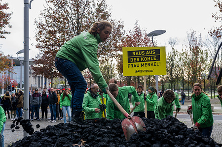Greenpeace activists are seen while spreading the unloaded coal on the floor during a demonstration. Greenpeace activists have unloaded 10 tonnes of coal in front of the Chancellery in Berlin. With the action, they want to lend her demand for a quick coal exit. The future climate and energy policy is at the heart of the Jamaica exploratory talks of Union, FDP and Bündnis 90 / Die Grünen in Berlin.