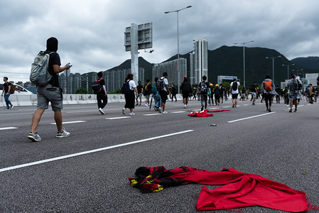 A burned and tattered Chinese flag lies on the ground as protesters walk away from the airport during the demonstration.
Anti-government protesters occupied roads leading toward Hong Kong International Airport in support of the anti-extradition movement. Protesters used barricades the block highways, forcing airport staff and passengers to walk along the road to reach the airport. So far, the government has yet to yield to any of the protesters’ 5 demands, including the full withdrawal of the extradition bill.