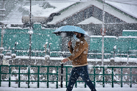 A man holds an umbrella as he walks through a snow covered road during heavy snowfall in Srinagar.
Most areas of the Kashmir valley on Wednesday received snowfall – the season’s first heavy fall in the plains – disrupting flight and railway operations and leading to the closure of the vital Srinagar-Jammu national highway, officials here said.