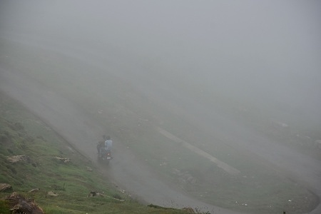 A motorcyclist rides through a road during foggy weather on the outskirts of Srinagar. Light to moderate rains continued to lash Kashmir and Meteorological Department has predicted fairly widespread light to moderate showers in the next 24 hours.