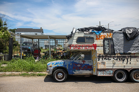 A graffiti-covered RV draped with tarps is parked in the Lower 9th Ward neighborhood of New Orleans. On August 29, 2005, Katrina struck the Gulf of Mexico, devastating the city of New Orleans in the United States. Twenty years later, although physical reconstruction has taken place, its residents still suffer from psychological disorders such as anxiety, depression, and post-traumatic stress.