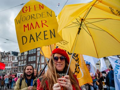 A protester is holding a yellow placard that says " No words, but roofs" during the demonstration. People gathered against the worsening housing crisis. Under the motto “Houses for people, not for profit,” they demand fundamental changes in Dutch public housing.