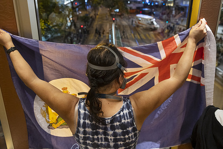 A protester holds up a Union Jack flag while standing on a pedestrian bridge watching police movements.
Pro-democracy demonstrators took to the streets to mark the first year anniversary of anti-extradition bill movement in Central district, Hong Kong.