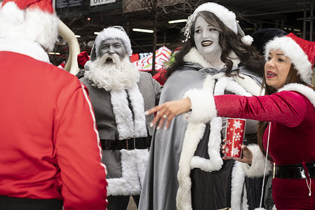 Monochromatic Santa and Mrs. Claus pose for photos. The annual charity event 'Santacon' took place in Times square where most participants dress in a Santa, Mrs. Claus or grinch outfit in a traditional or creative way.
