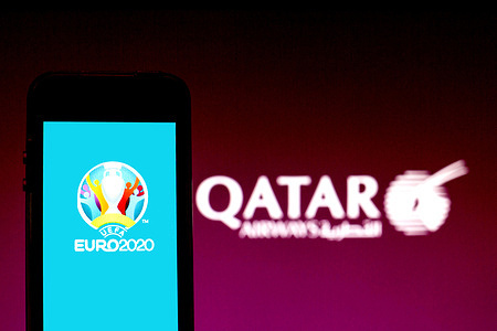 In this photo illustration a UEFA Euro 2020 logo seen displayed on a smartphone with a Qatar Airways logo in the background.