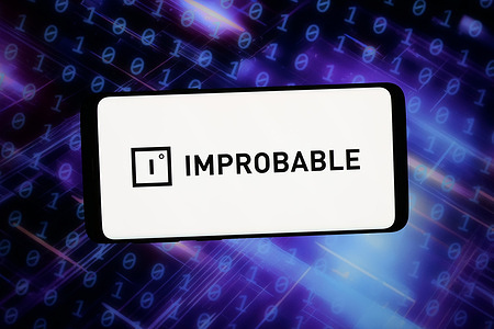 In this photo illustration, the logo of technology company Improbable Worlds Limited is displayed on a smartphone in front of abstract background on computer screen.