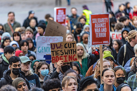 Protesters gather at the University of Washington's Red Square while holding placards during the demonstration. This event was hosted by "Super UW," a student-led organization dedicated to aligning itself with the liberation movement. Their promotional material, initially disseminated on Facebook earlier in the week, created a significant stir within the community. The flyer itself featured captivating artwork depicting individuals brandishing signs and flags bearing slogans such as "Free Palestine" and "Advocating for UW to sever ties with the Boeing company," while others made peace signs with their hands, further accentuating the message of peace and justice.