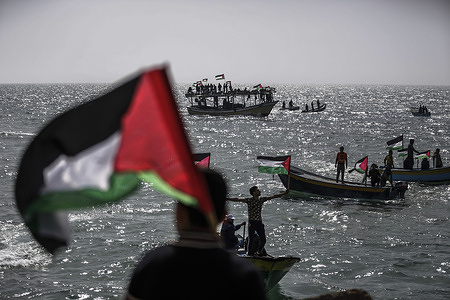 Palestinian fishers are on their boats while waving their national flags during a rally marking the 46th anniversary of Palestinian Land Day in the Mediterranean Sea at the fishermen's port in Gaza City. The 46th anniversary of Land Day marks an incident in 1976 when Israeli troops shot and killed six people during protests against land confiscations.