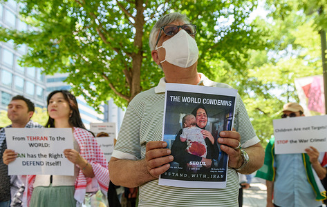 Iranians hold placards during a rally demanding to stop the war between Israel and Iran.