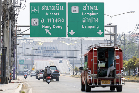 Vehicles travel along a road beneath directional signs toward Hang Dong, Lamphun, and Lampang, as haze from elevated PM2.5 levels reduces visibility amid ongoing wildfire conditions.