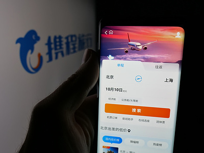In this photo illustration, a smartphone with the web page of Chinese online travel company Ctrip on screen in front of logo.
