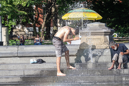 Park goers cool off in the water fountain in Washington Square Park amid a heat wave on July 2, 2026 in New York City.