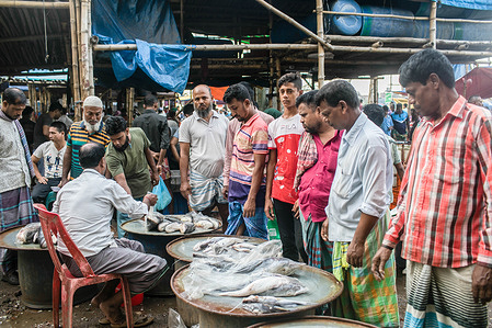 Customers look at fish displayed for sale at a local fish market next to the Buriganga River in Dhaka,