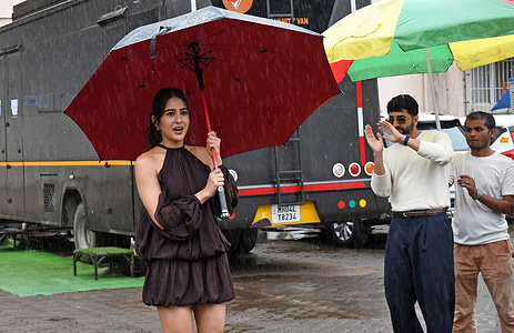 Bollywood actress Sara Ali Khan (L) poses for a photo whiie holding an umbrella as she promotes her upcoming film 'Udta Teer' at a studio in Mumbai.