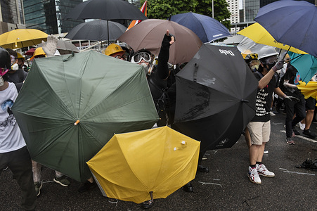 Anti government protester shouts at the police while using using umbrellas as shields to protect themselves from the police during the standoff. Thousands of anti government protesters faced off with riot police and occupy major roads around the Hong Kong government complex during the 22nd anniversary of Hong Kong return to Chinese rule.