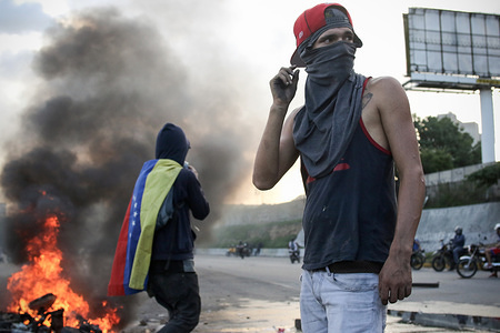 An anti-government demonstrator stands by a burning motorcycle protesters took away from National Guards who blocked them from marching to the office of Attorney General Luisa Ortega Diaz to show support for the one-time government loyalist.
Venezuela's Supreme Court cleared the way for the prosecution of the country's chief prosecutor, who became a surprise hero to the opposition after breaking ranks with the government of President Nicolas Maduro over his efforts to concentrate power.
