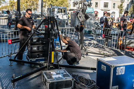 Two sound technicians prepare equipments for the media at Passeig de Gràcia.
While the Spanish President Mariano Rajoy told at a press conference the new powers to suspend the autonomy of the Catalan authority, Barcelona prepares in the great shopping Avenue of Passeig de Gracia a new demonstration of the Catalan independence movement to demand the freedom of the two political prisoners Jordi Cuixart and Jordi Alvàrez. Throughout the morning national and international television and media have been deploying its equipment front of the indifferent eyes of citizens and tourists. This display of media has not varied routines of consumers or customers of the bar terrace.