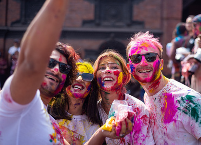 People smeared with vermilion powder smile during the Holi festival celebration. The Holi festival is celebrated to mark the victory of good over evil and also symbolizes the arrival of the spring season.
