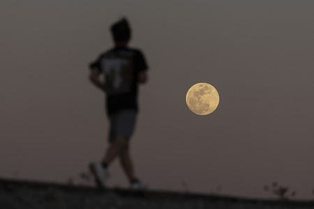 The full Worm Moon rises over Los Angeles on March 2, 2026, as a man runs past ahead of a total lunar eclipse.