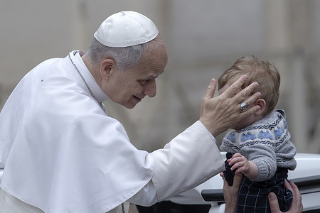 Pope Leo XIV greets a child as he leaves at the end of his weekly general audience in St. Peter's square.