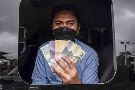 An employee on duty in a mobile money exchange from Bank Indonesia (BI) shows shows bundles of notes. In the run-up to Eid al-Fitr, Bank Indonesia provides mobile money exchange cars so people can exchange large notes for low-value ones, which the bank will later distribute to relatives as Hari Raya Allowance (THR).