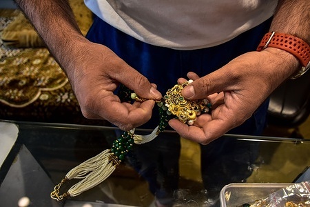 A jeweler holds a gold pendant at his shop in Srinagar, the summer capital of Jammu and Kashmir. India raised import tariffs on gold and silver in an attempt to defend its currency, as the country races to shore up foreign-exchange reserves and limit the damage from the war in the Middle East. The government more than doubled import taxes on gold and silver to about 15% from 6%, imposing a 10% basic customs duty alongside a 5% agriculture infrastructure and development levy.